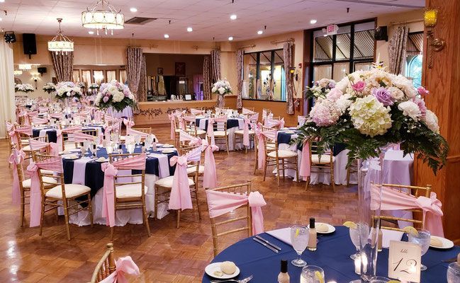 A large room with tables and chairs set up for a wedding reception.