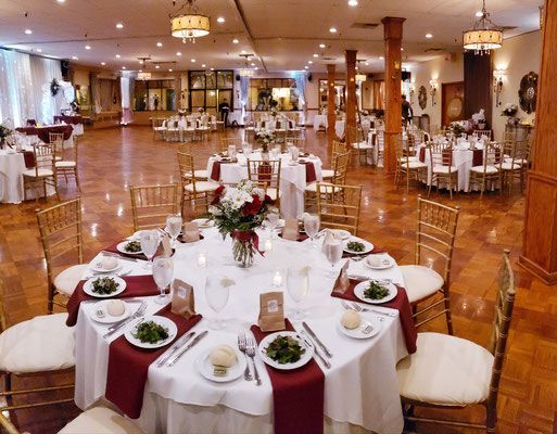 A large room with tables and chairs set up for a wedding reception