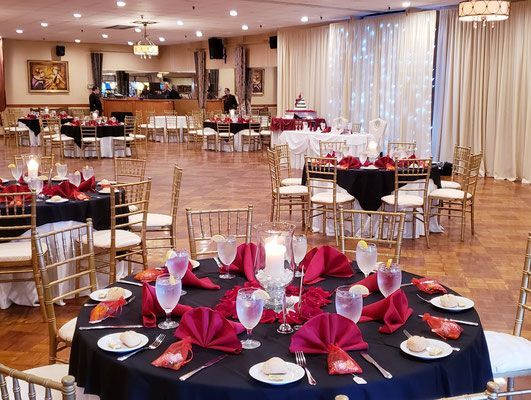 A large room with tables and chairs set up for a wedding reception