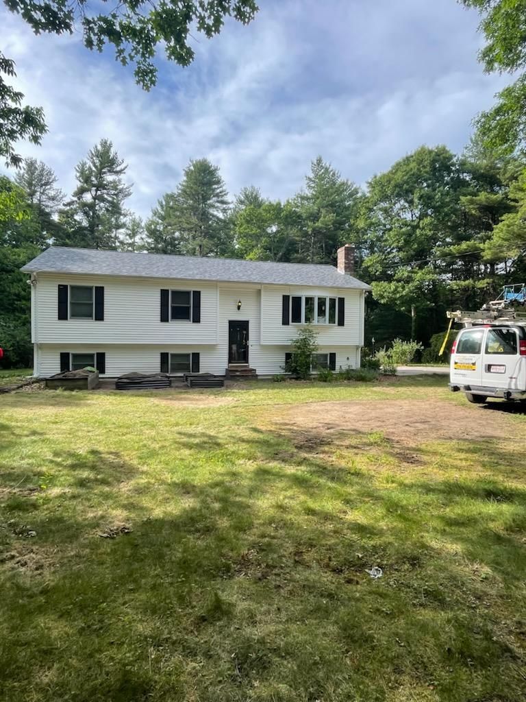 White, one-story house with black shutters, on a grassy lot. A white van is parked nearby. Sunny day.
