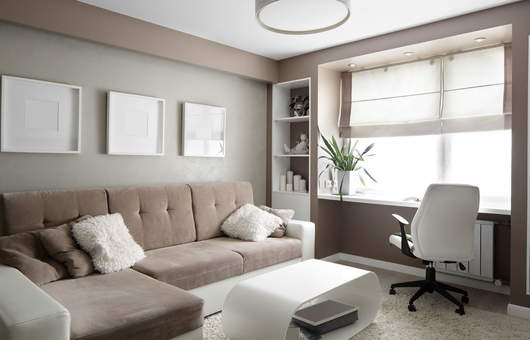 Cozy living room with beige sofa, white office chair, desk by window, and soft neutral decor.
