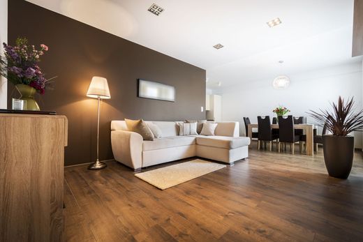 Modern living room with white sectional sofa, floor lamp, wooden floor, and dining area in the background