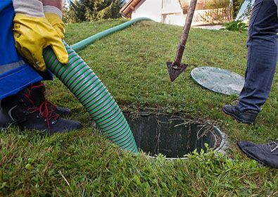 A person is pumping water into a septic tank with a hose.