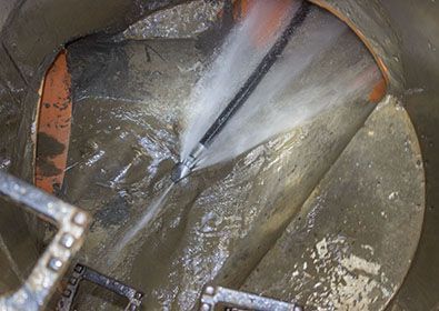 A hose is being used to clean a drain.