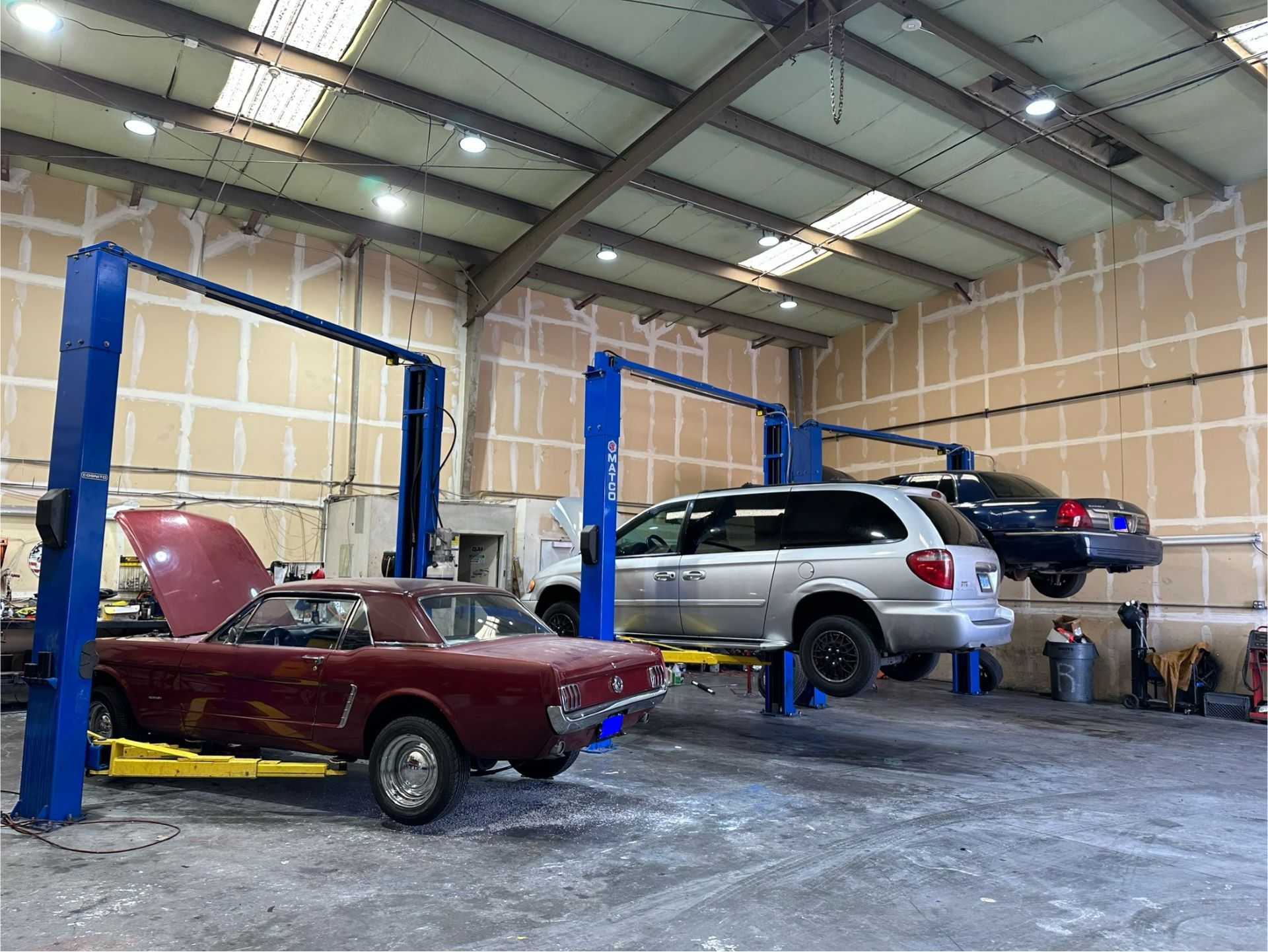 Two cars are sitting on a lift in a garage.