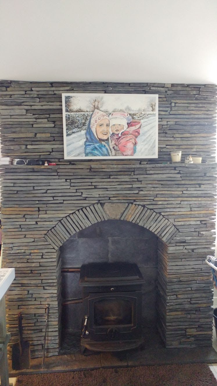 A stone fireplace with a cast iron stove and a framed portrait hung on the mantel.