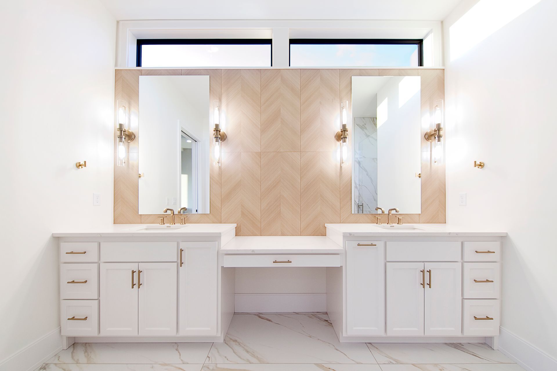 White bathroom with his and hers vanities, mirrors, and herringbone tile accent wall.