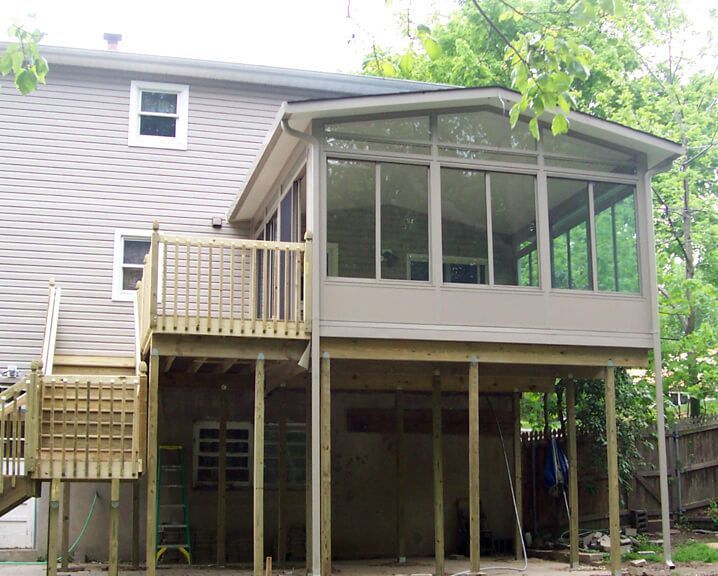 Back of a two-story house with a wooden deck and screened-in porch addition.