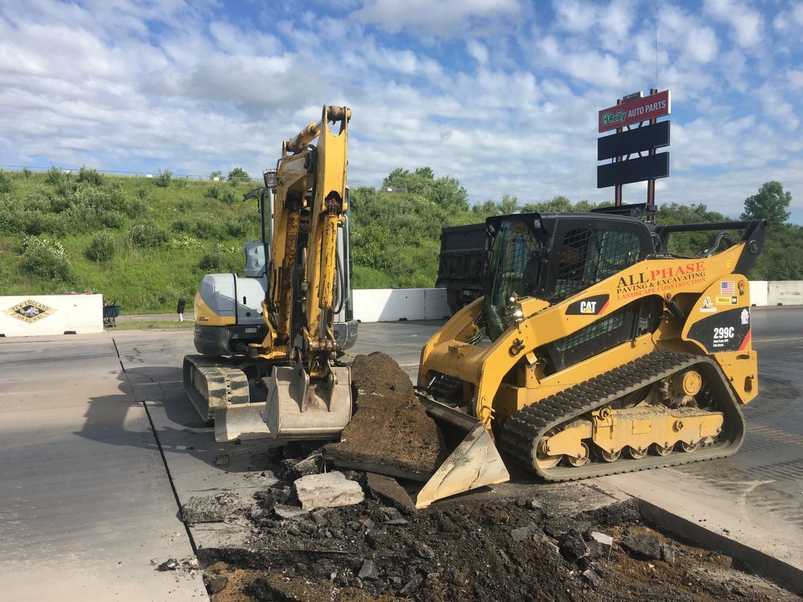 Yellow excavators working on road surface.