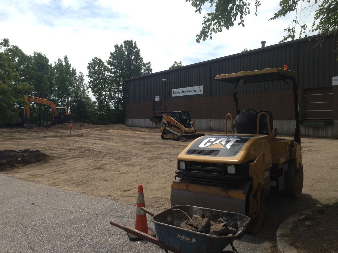 Construction site with a roller and other equipment in front of a building.
