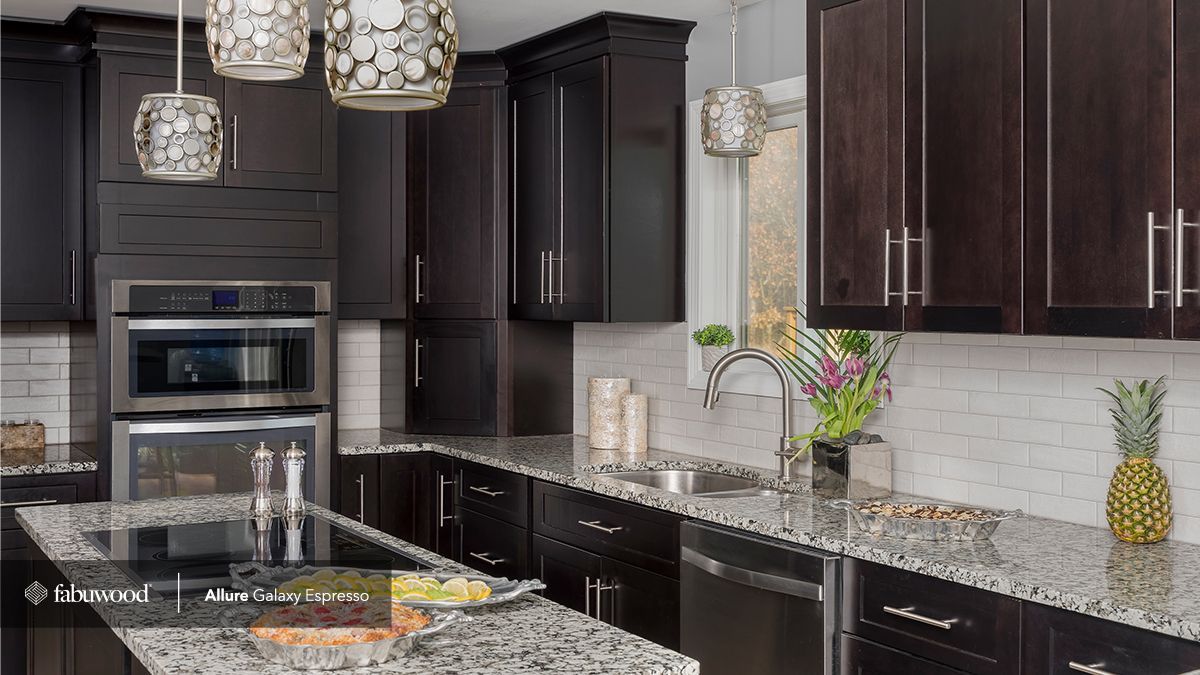 A kitchen with black cabinets and granite counter tops.