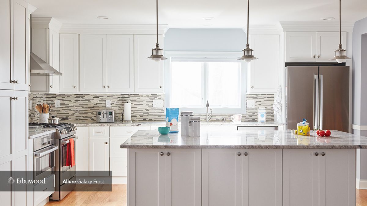 A kitchen with white cabinets, stainless steel appliances, and a large island.