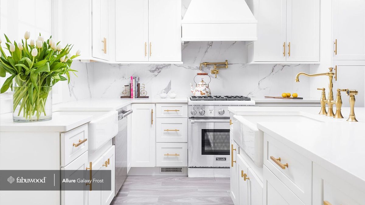 A kitchen with white cabinets, a stove, a sink, and a vase of flowers.