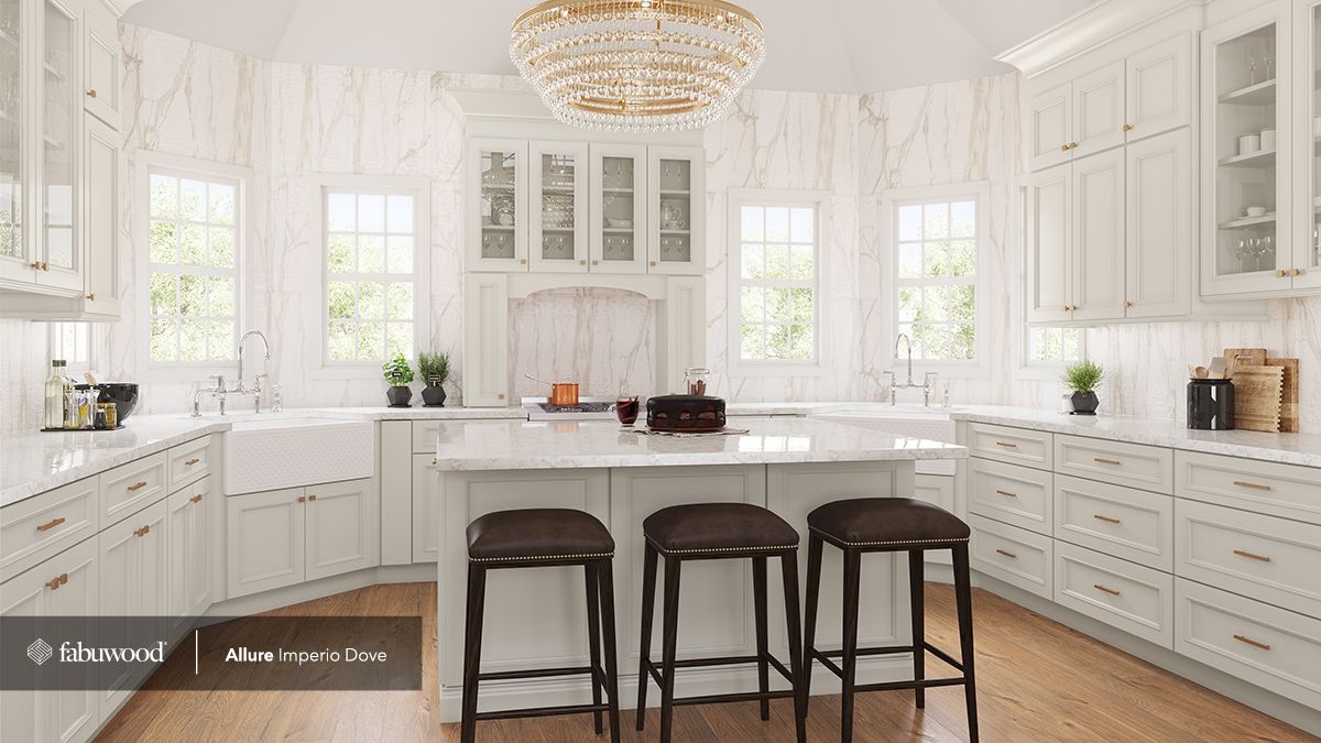 A kitchen with white cabinets, a large island, stools, and a chandelier.