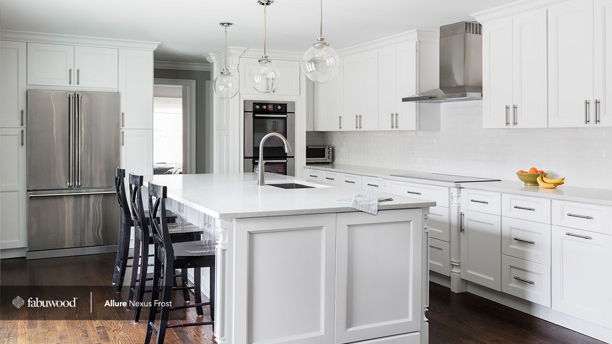 A kitchen with white cabinets, stainless steel appliances, and a large island.