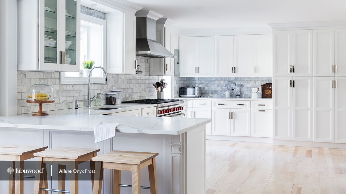 A kitchen with white cabinets, stools, a stove, and a window.