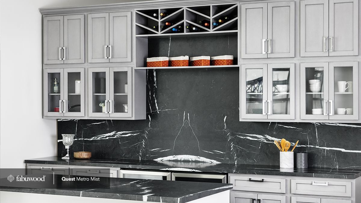 A kitchen with gray cabinets and black countertops