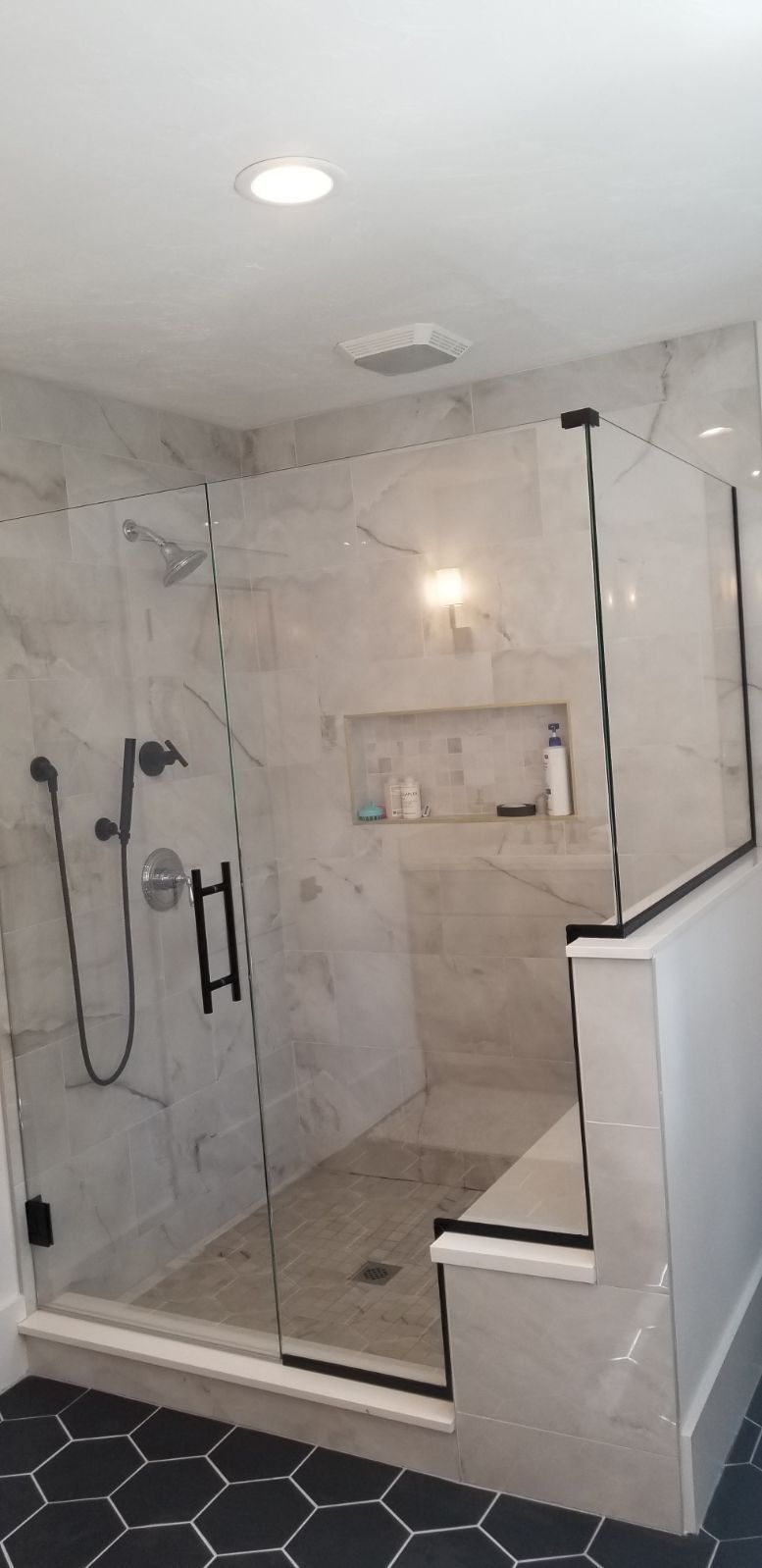 A bathroom with a walk in shower with a glass door.