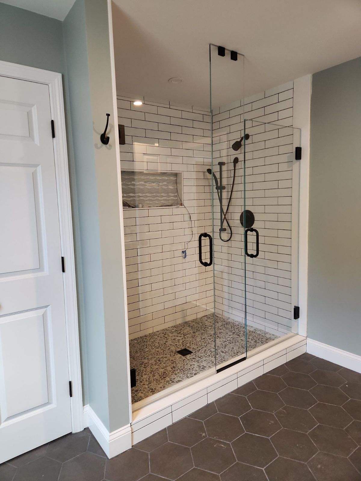 A bathroom with a walk in shower with a glass door.
