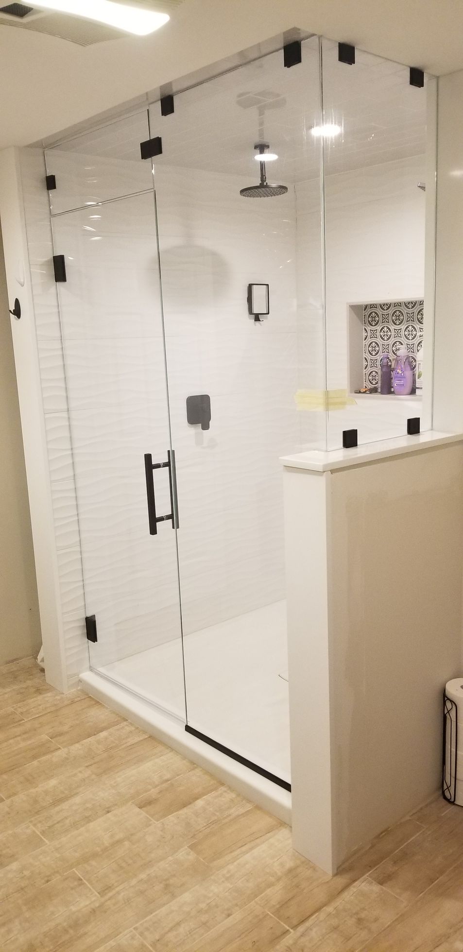 A bathroom with a walk in shower with a glass door.