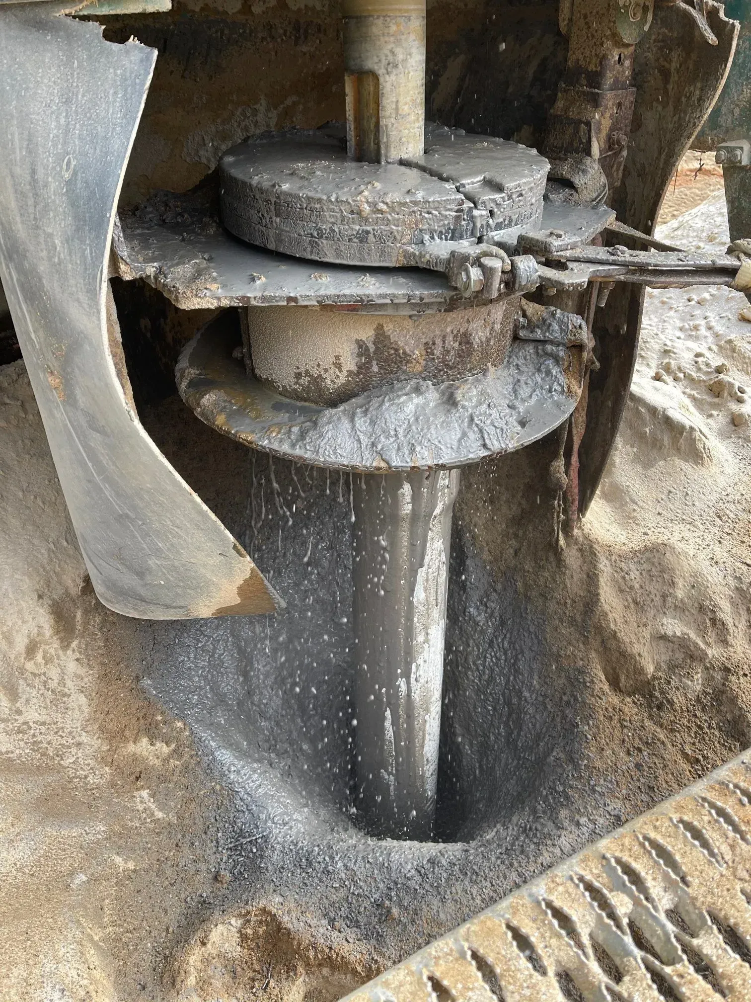Drilling rig creating a deep hole in the ground, close up view of the drill bit and surrounding earth.