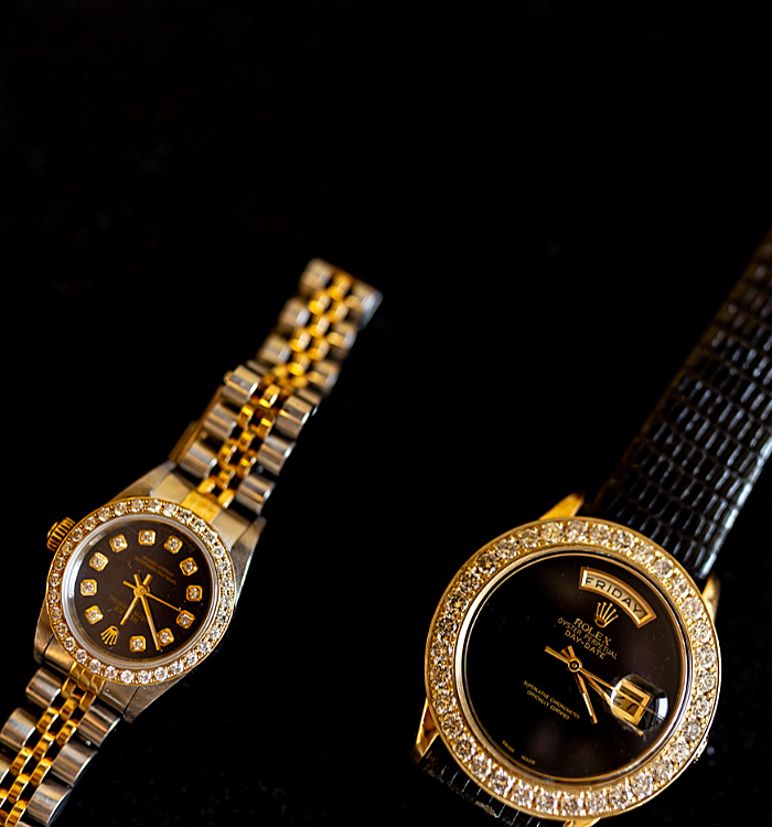 Two Rolex watches are on a black surface.