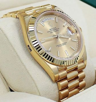 A gold Rolex watch is sitting on a white cloth.
