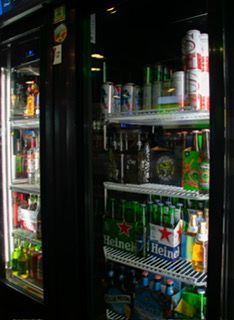 Refrigerated display case filled with various beverages including Heineken and canned drinks.