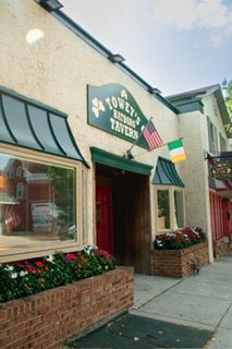 Exterior of Towey's Tavern, an Irish pub with American and Irish flags, red door, and window boxes of flowers.