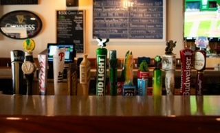 Bar counter with various beer taps and a Guinness sign in the background.