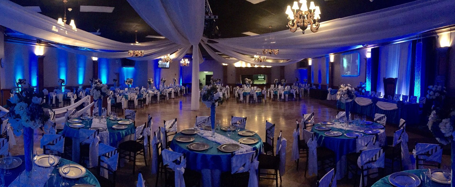 A banquet hall decorated in blue with round tables set for a formal event.
