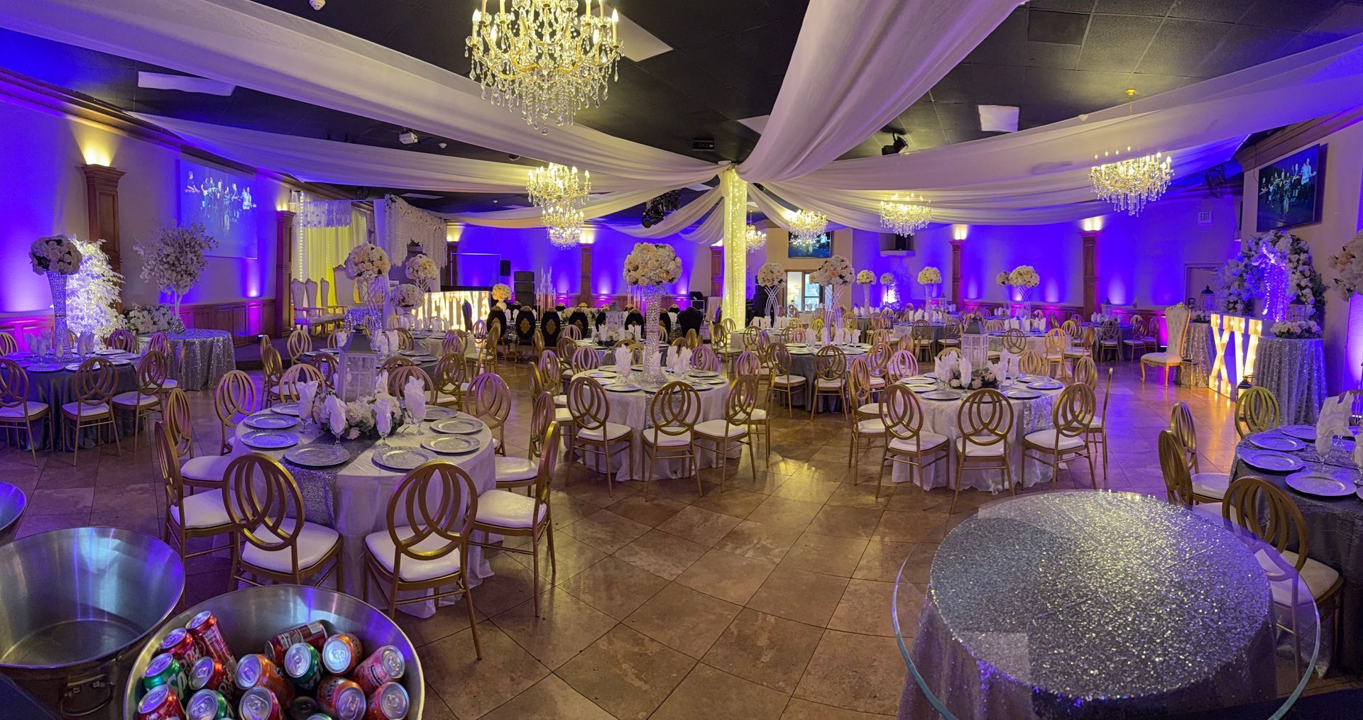 A banquet hall decorated in blue with round tables set for a formal event.