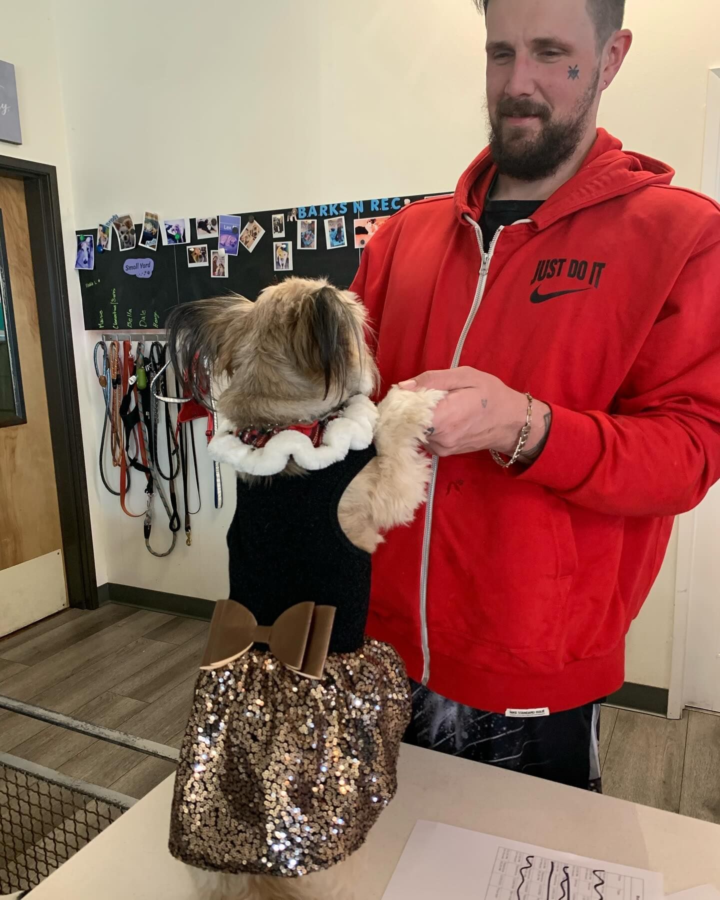 A man in a red nike jacket is holding a small dog
