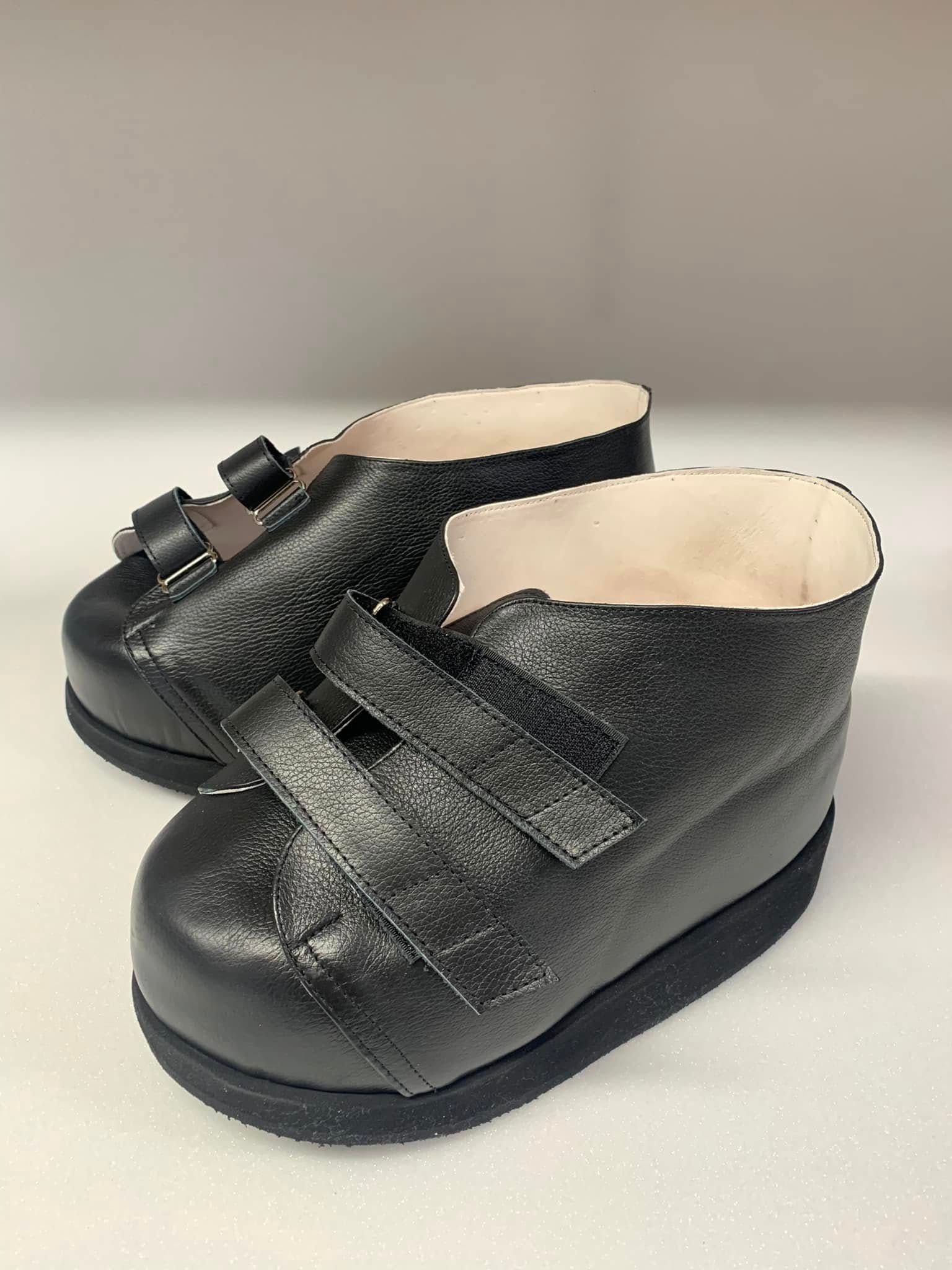 Pair of black orthopedic shoes with velcro straps.