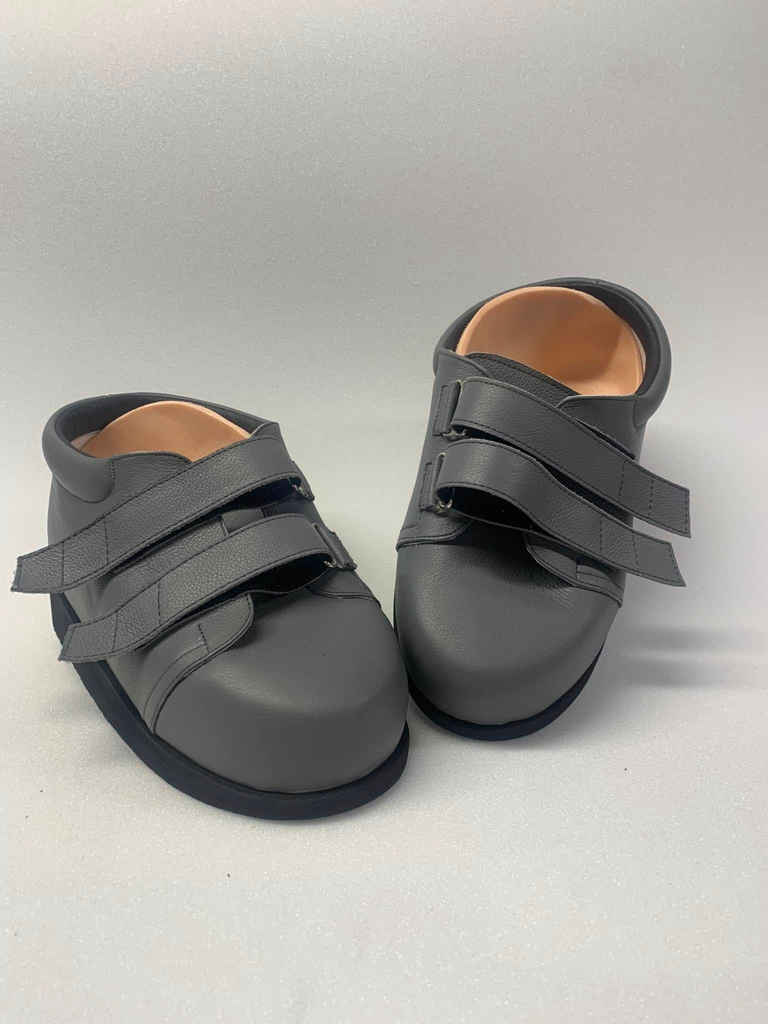 Pair of gray children's shoes with three hook and loop closures on a white background.