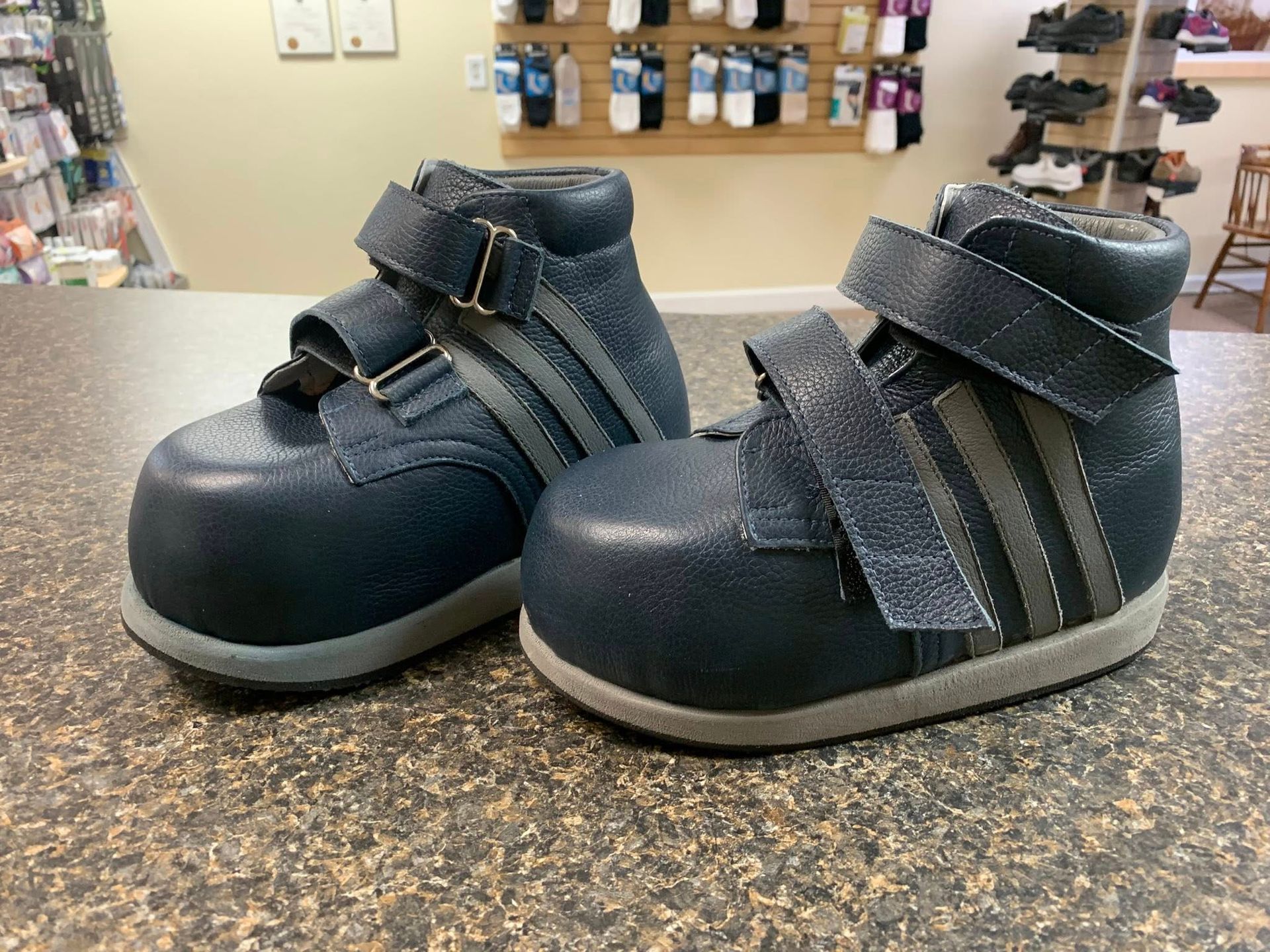 Two navy blue children's orthopedic shoes on a countertop, store setting.