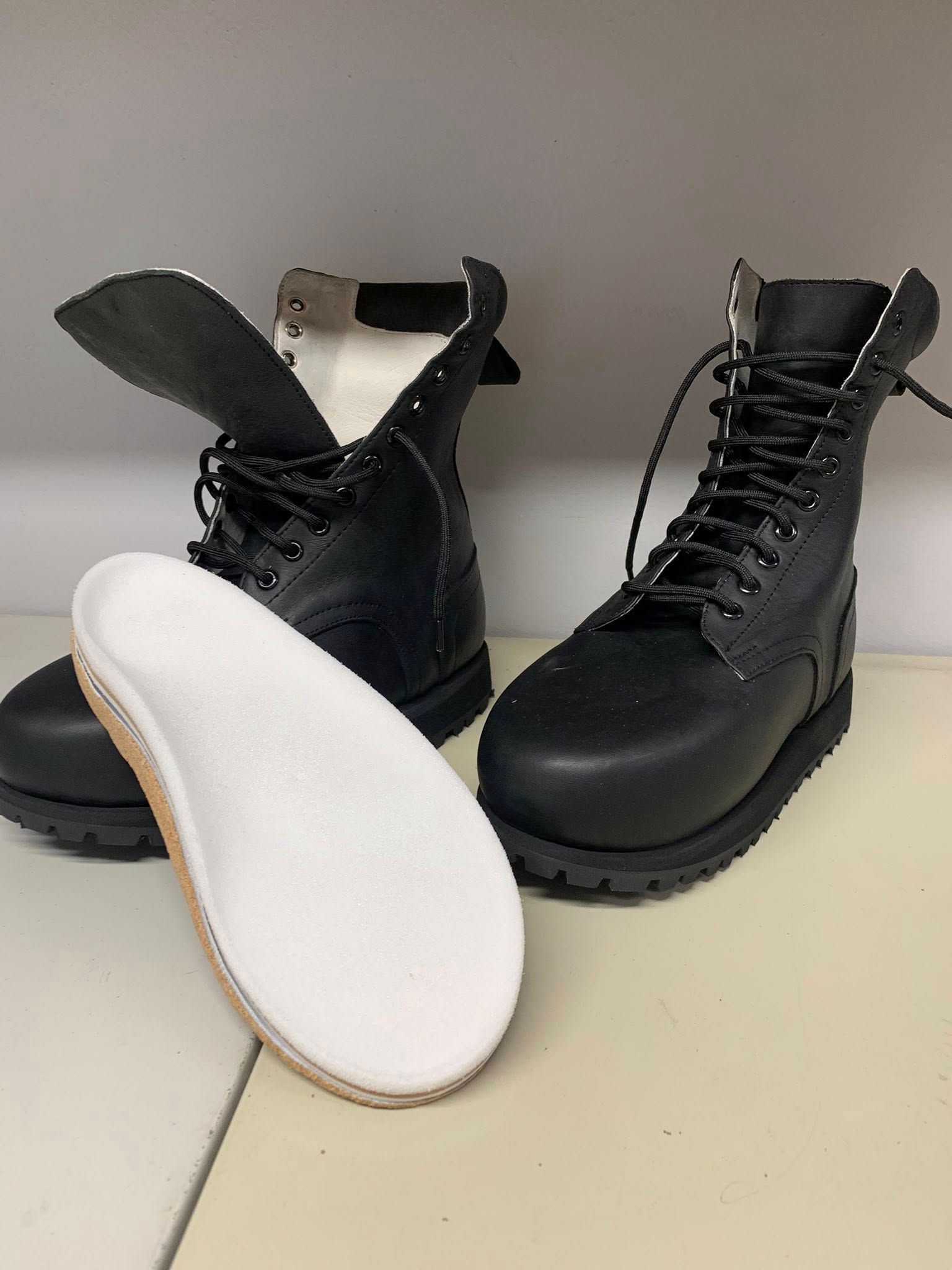 Black work boots with laces and a white orthopedic insole.