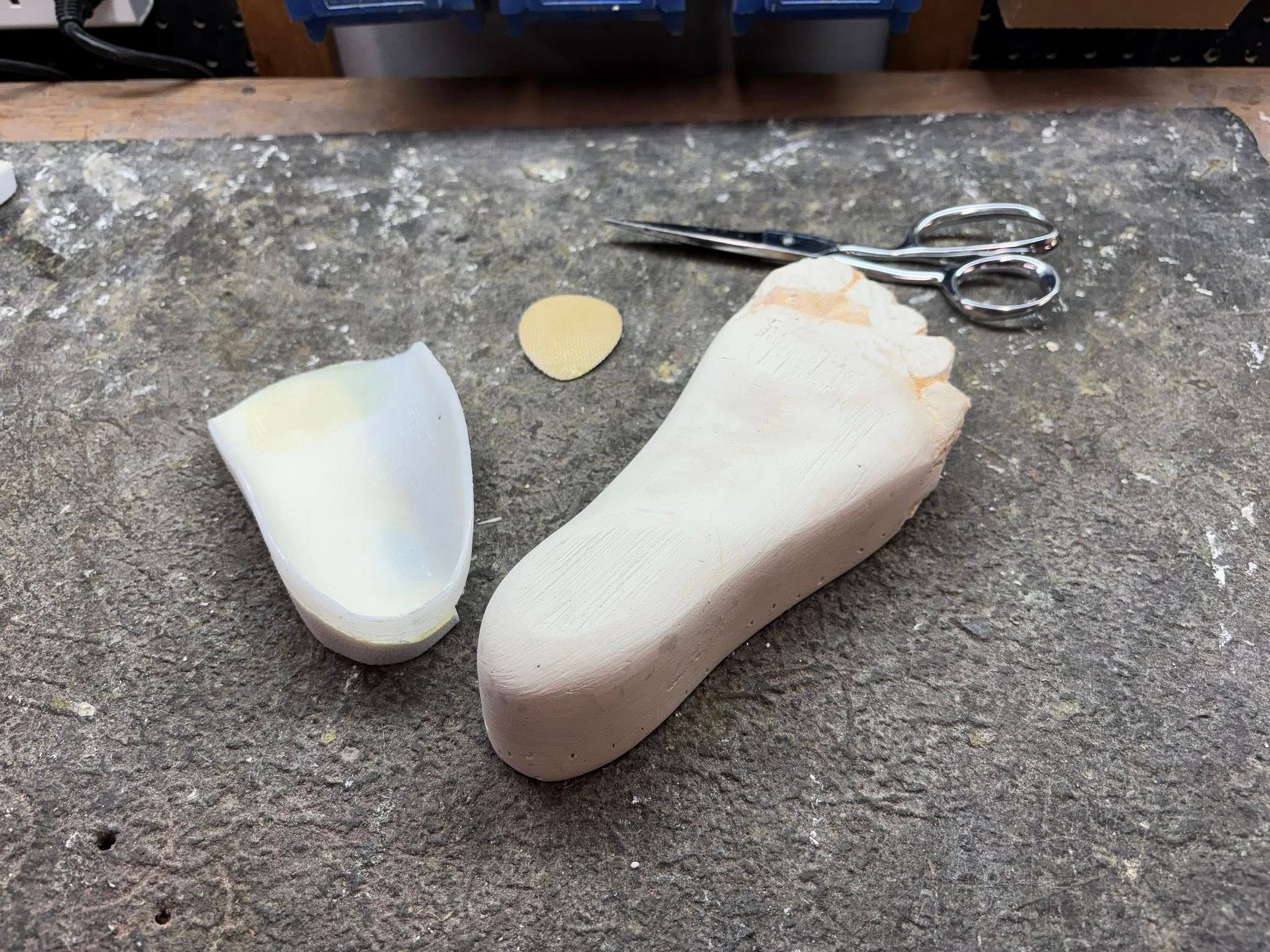 Foot orthotic components with scissors on a work surface.