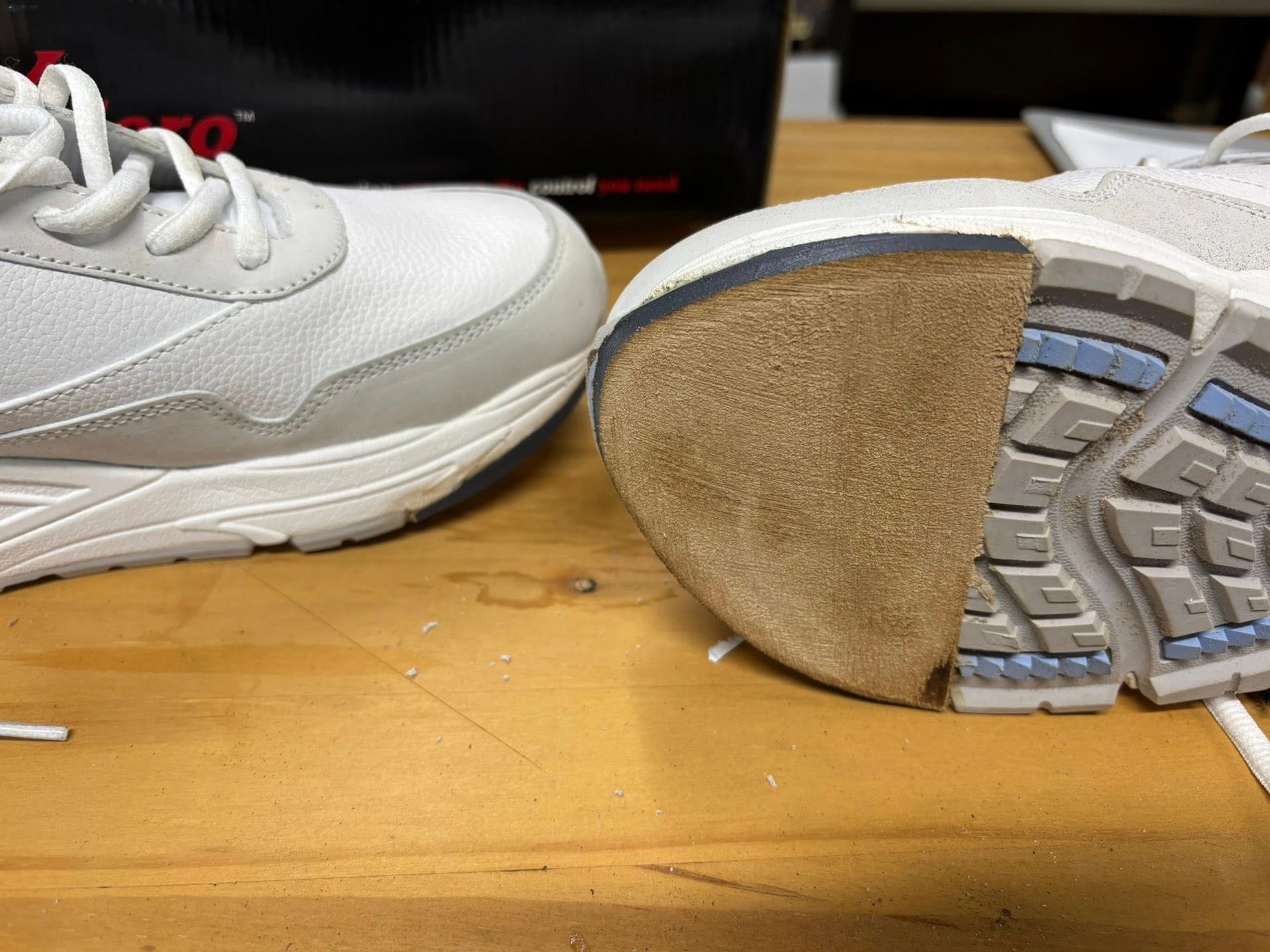 White athletic shoe cut in half, exposing the sole's layers and heel's textured beige foam.
