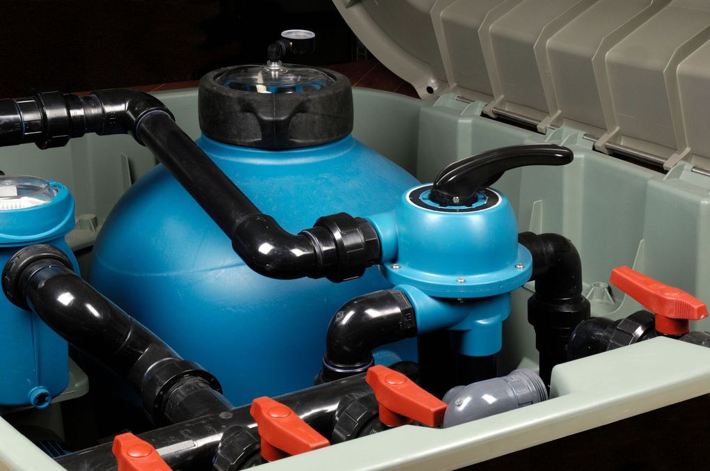 A blue pool sand filter system with black piping and several orange handle valves inside an open protective enclosure.