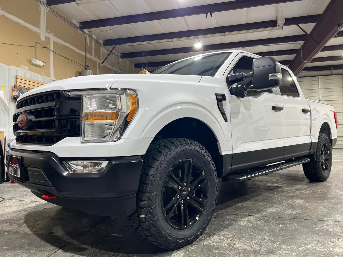 A white truck with black wheels is parked in a garage