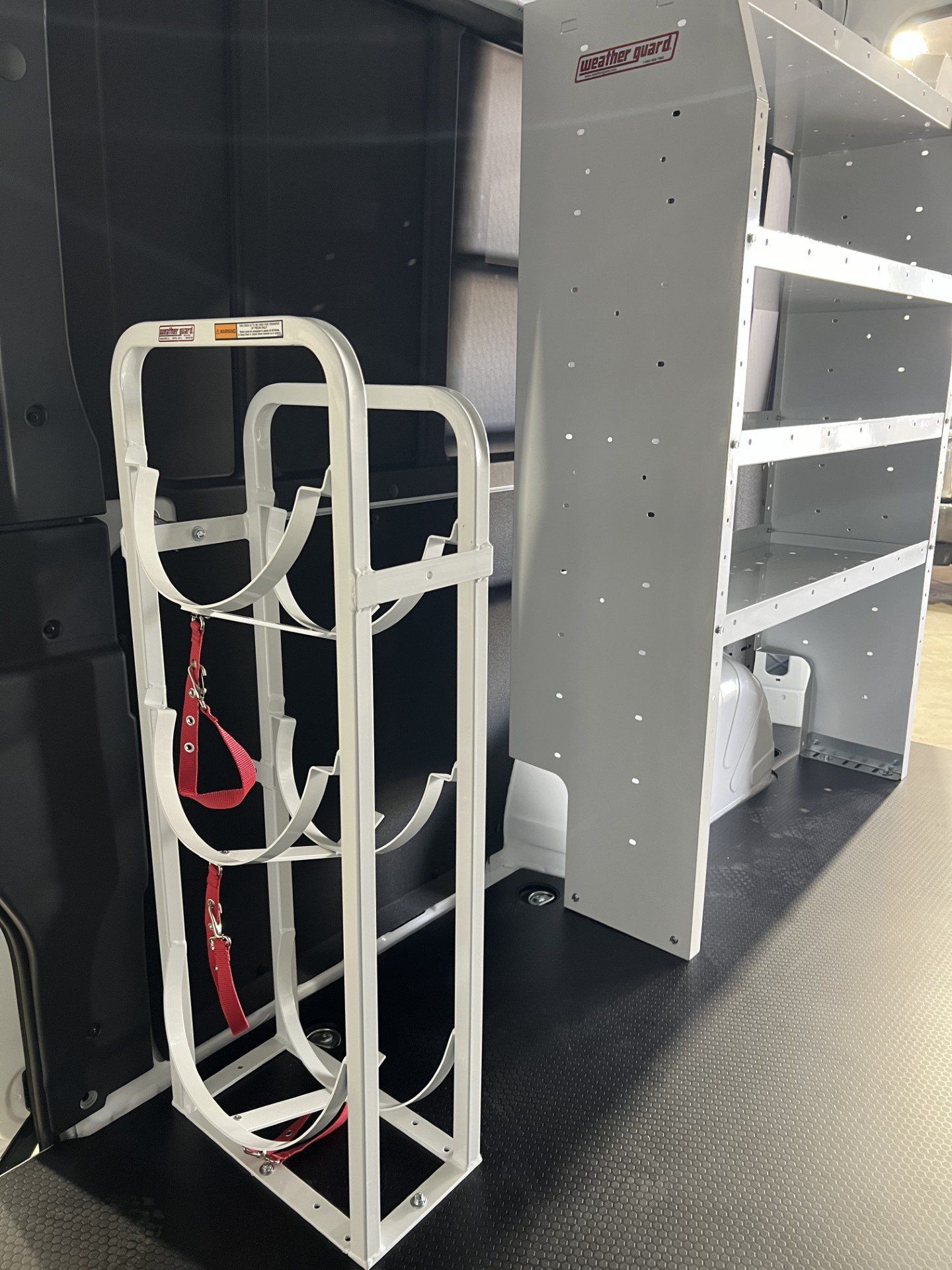 A white rack with a red strap is sitting next to a shelf.