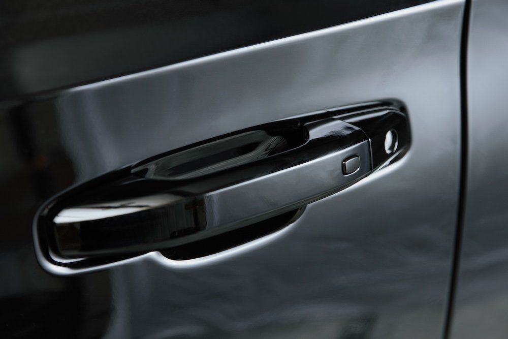 A close up of a black car door handle on a black car.