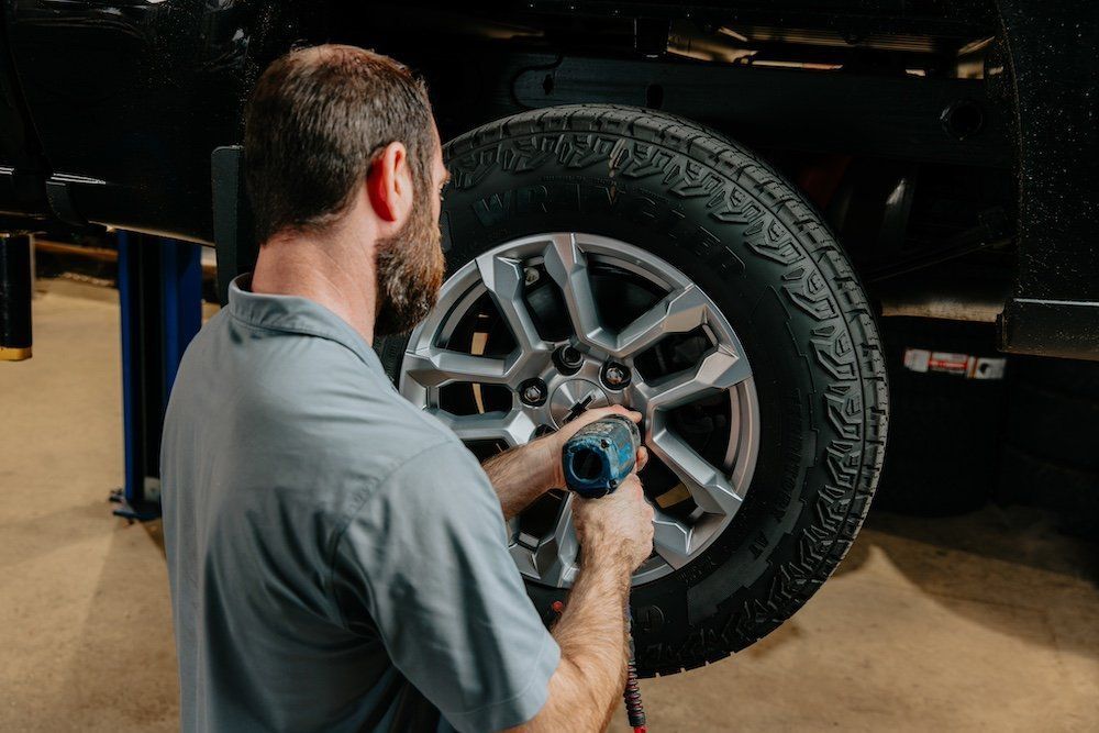 A man is changing a tire on a truck in a garage.