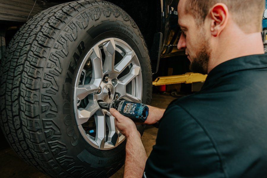 A man is changing a tire on a truck in a garage.