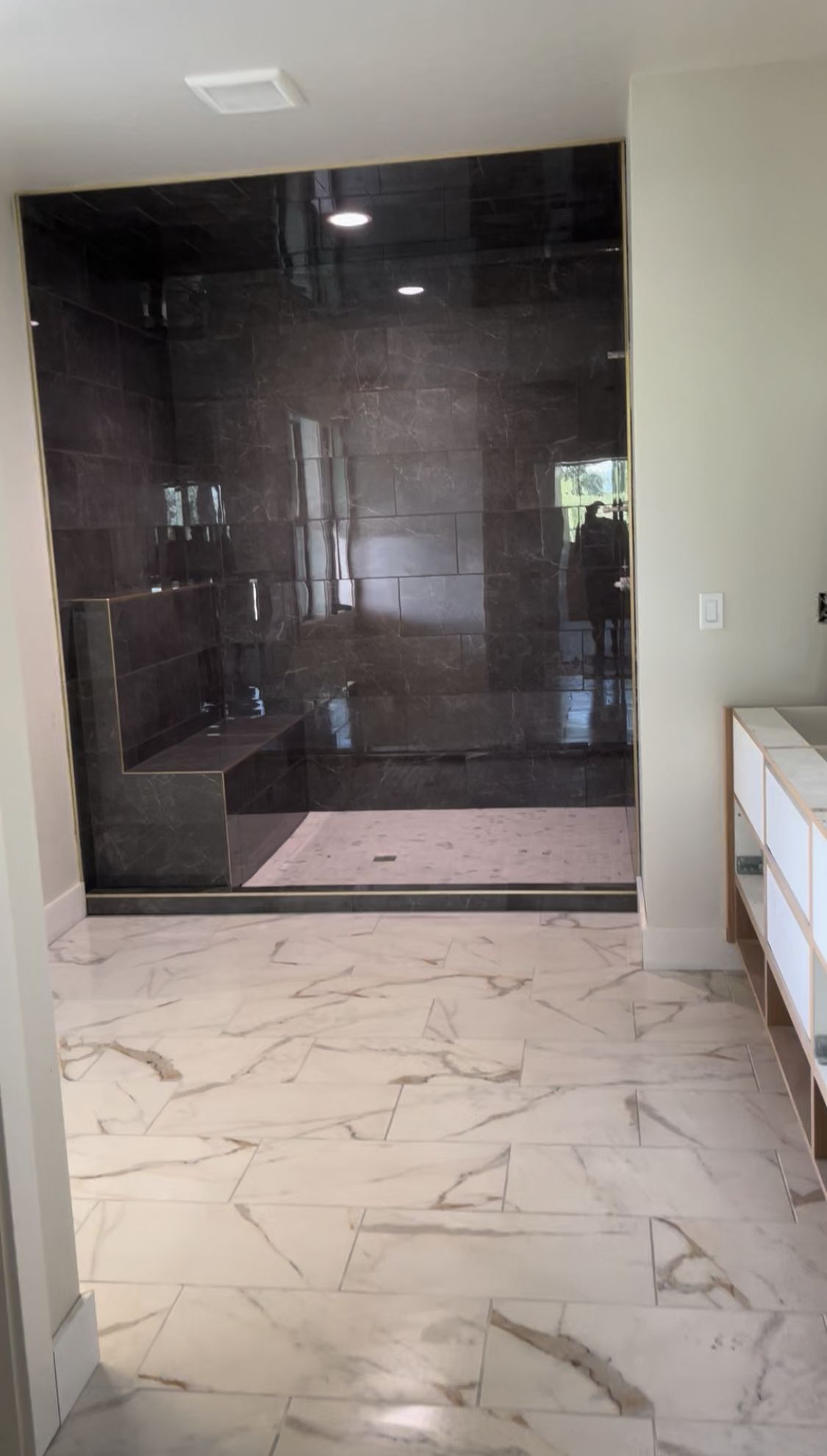 A bathroom with a walk in shower and a marble floor.
