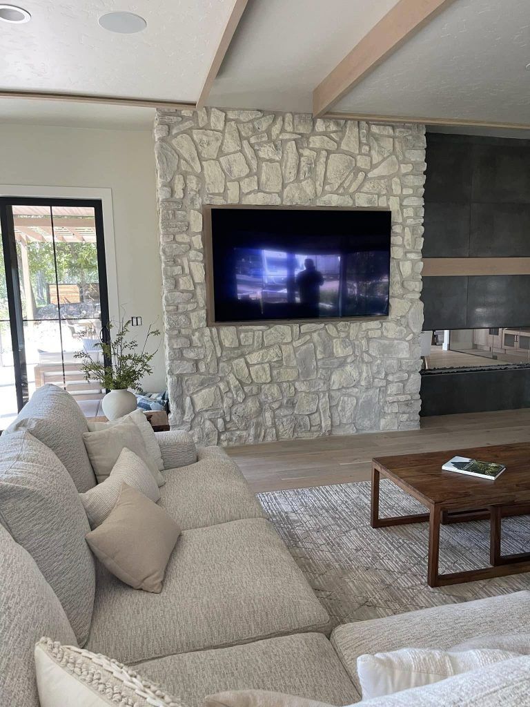 A living room with a couch and a flat screen tv on the wall.