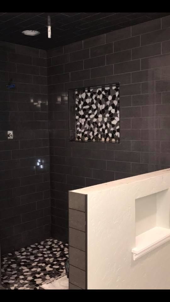 A bathroom with black tiles and a walk in shower.