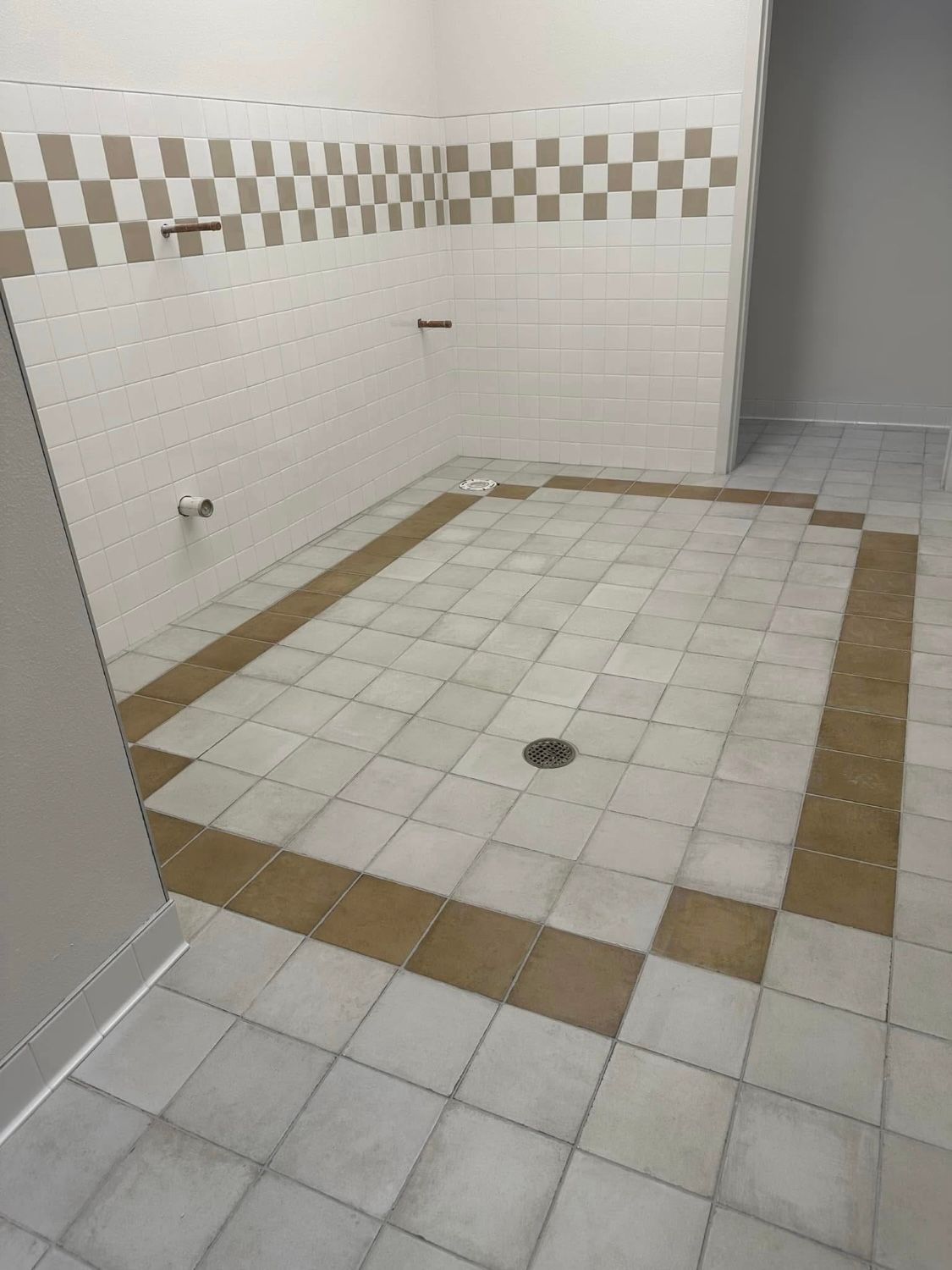 A bathroom with white tiles and a checkered wall.