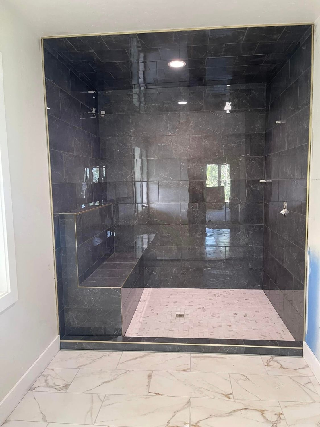 A bathroom with a walk in shower and a bench.